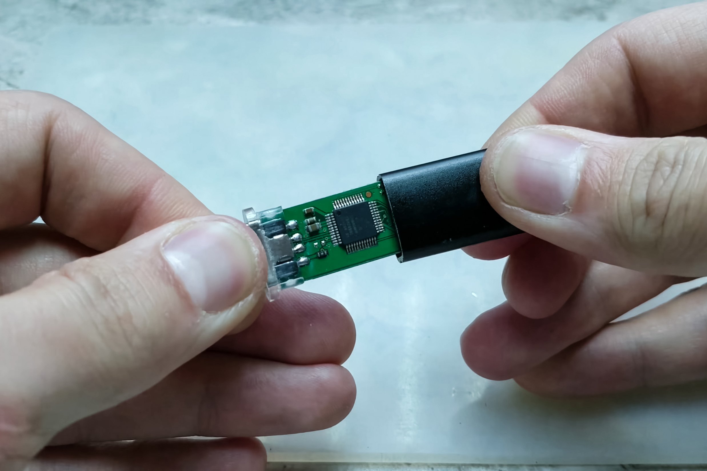 Two hands pulling out the guts of a USB stick.