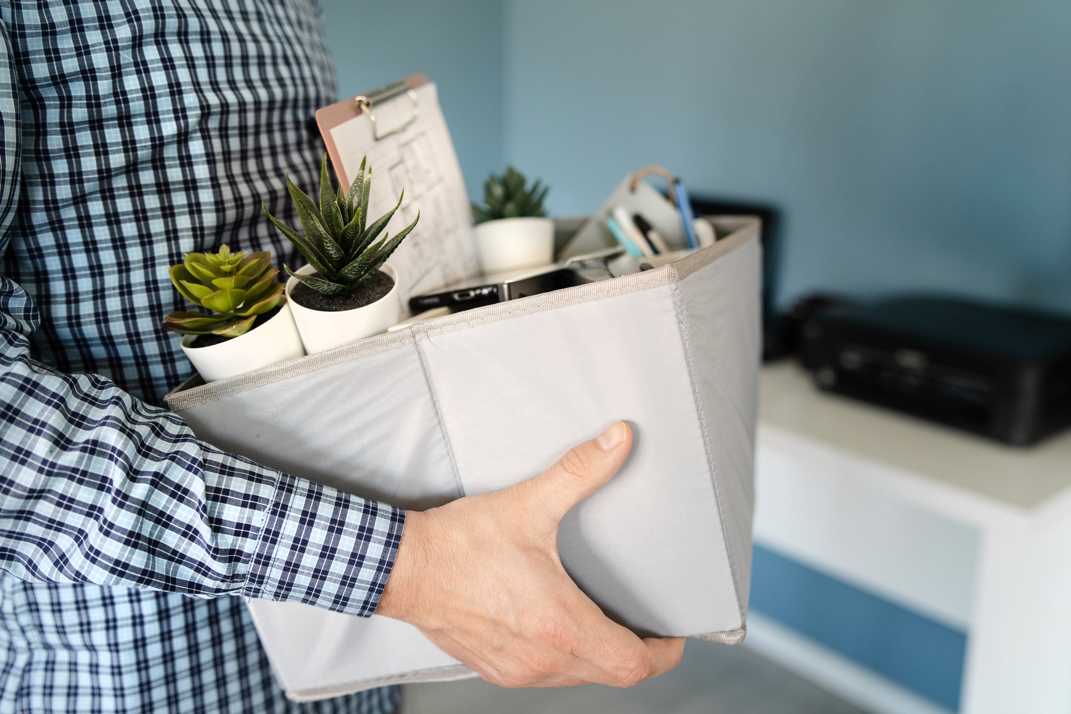 Man in an office holding box containing all of his work possessions.