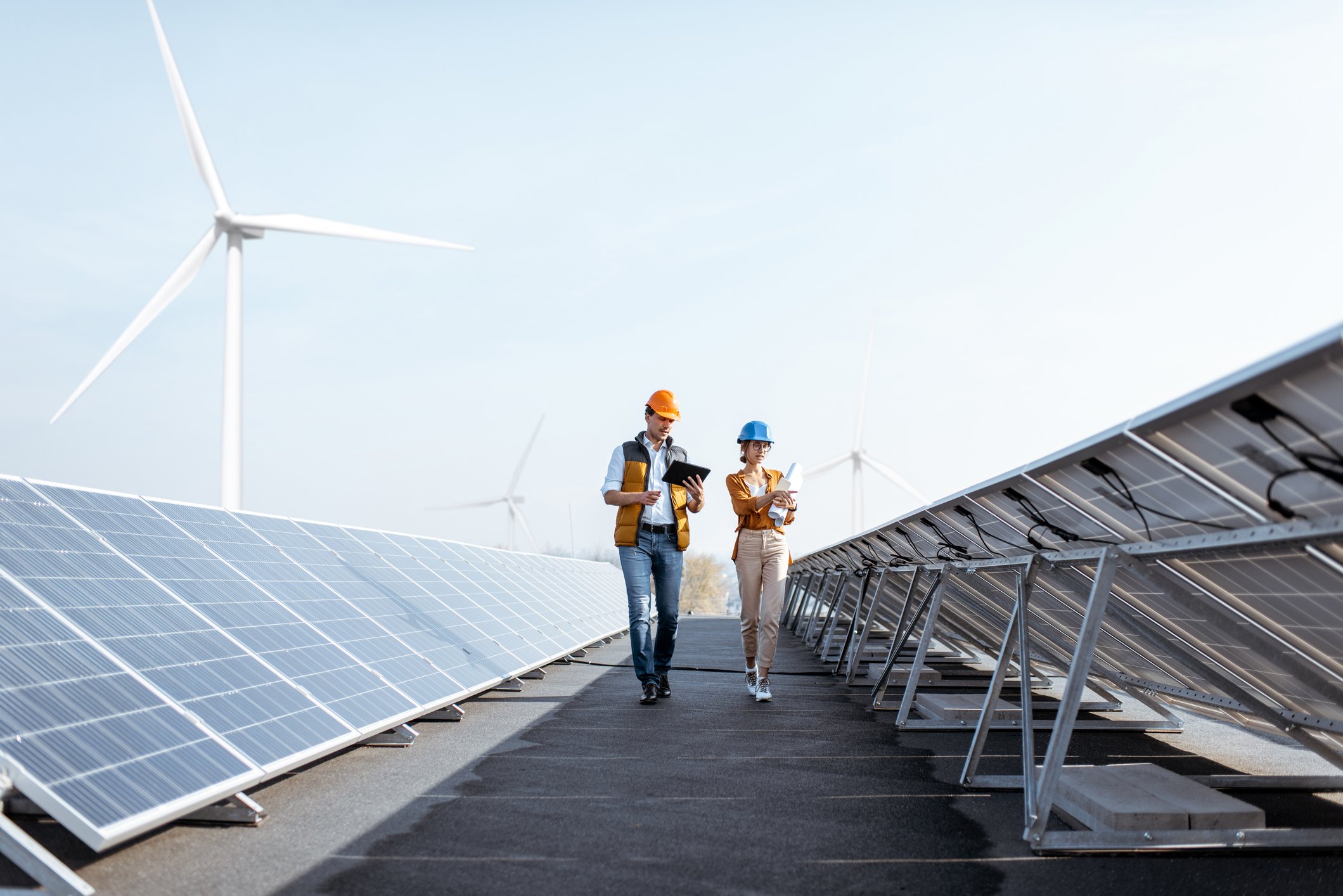 Engineers on a solar power plant with several windmills in the background.