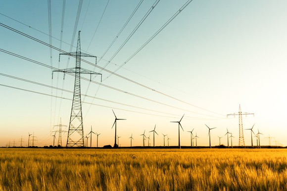 Power lines and wind turbines in a field.
