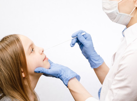 A clinician takes a nasal swab from a child.