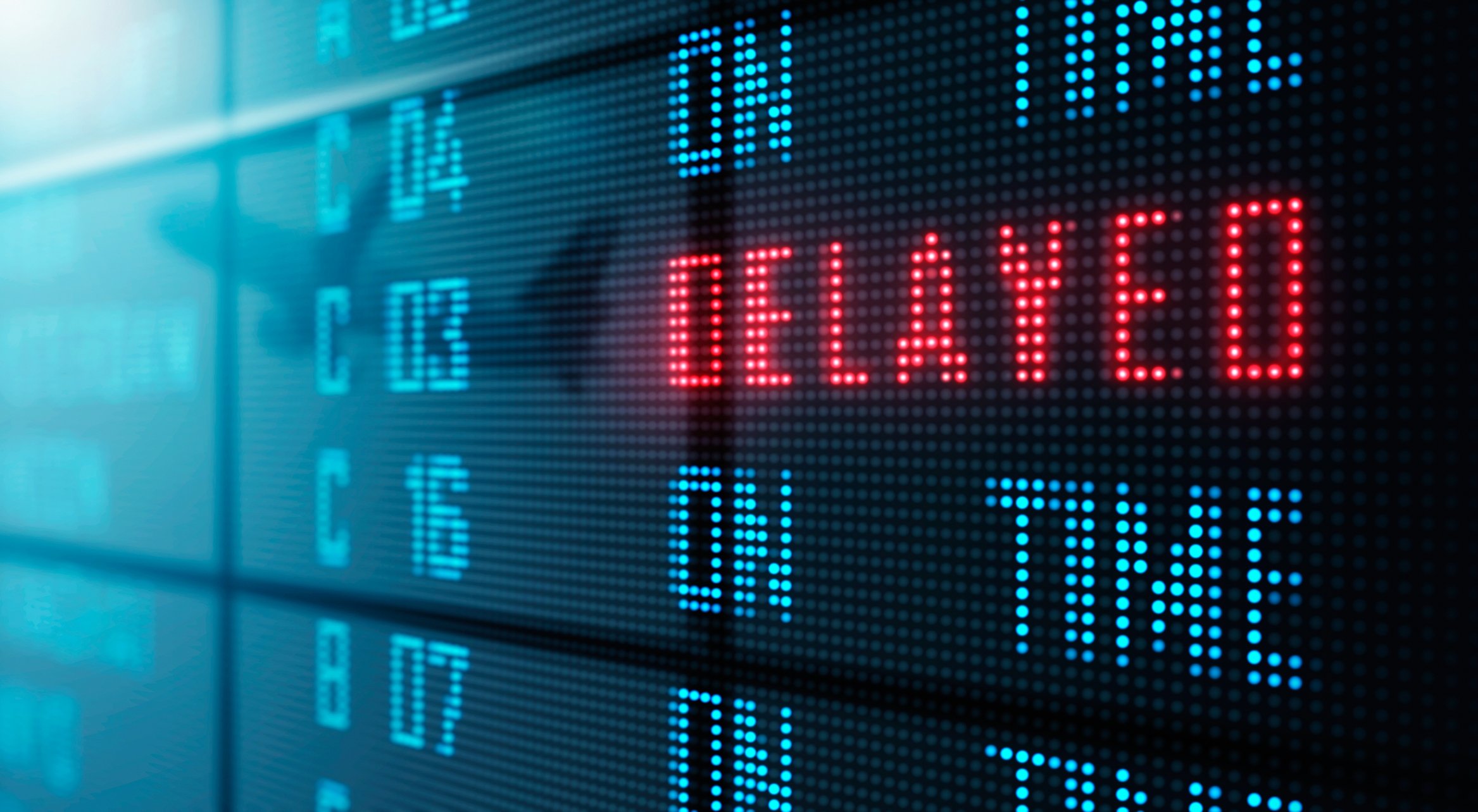 Airport flight schedule board reads DELAYED