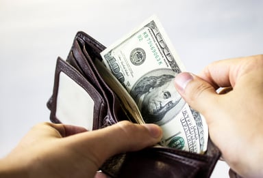 A person pulling a $100 bill out of a wallet.