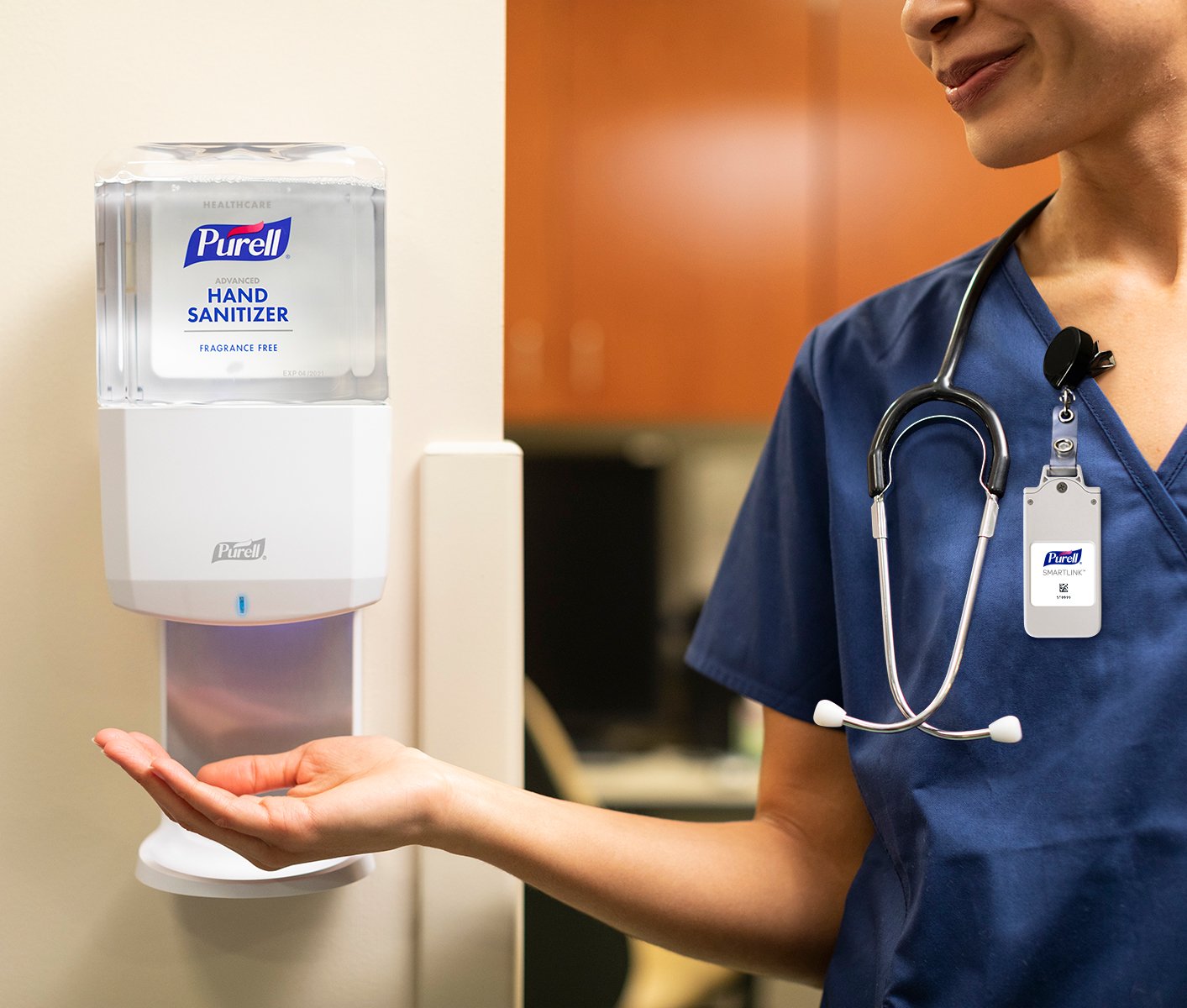 A nurse dispensing Purell at a hand sanitizing station.