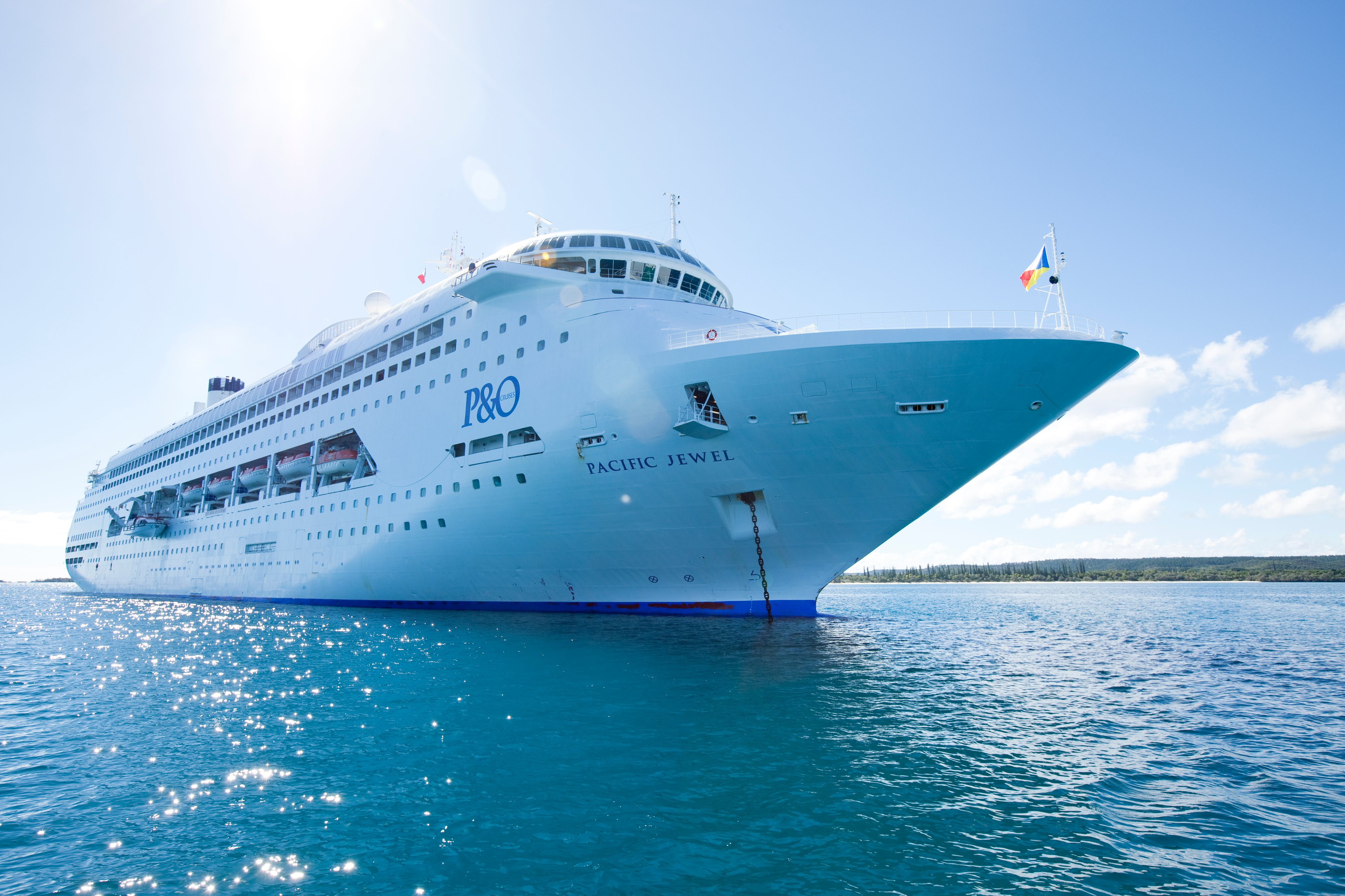 A waterline view of the Carnival ship "Pacific Jewel" on blue waters under a sunny sky.