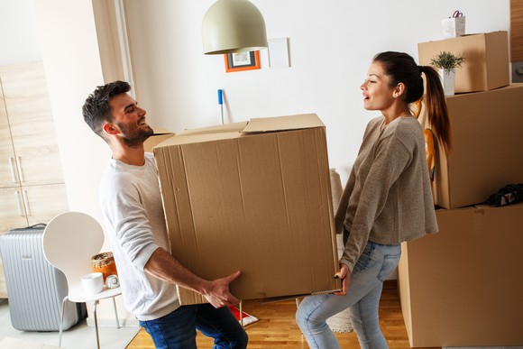 Young couple holding a moving box. 