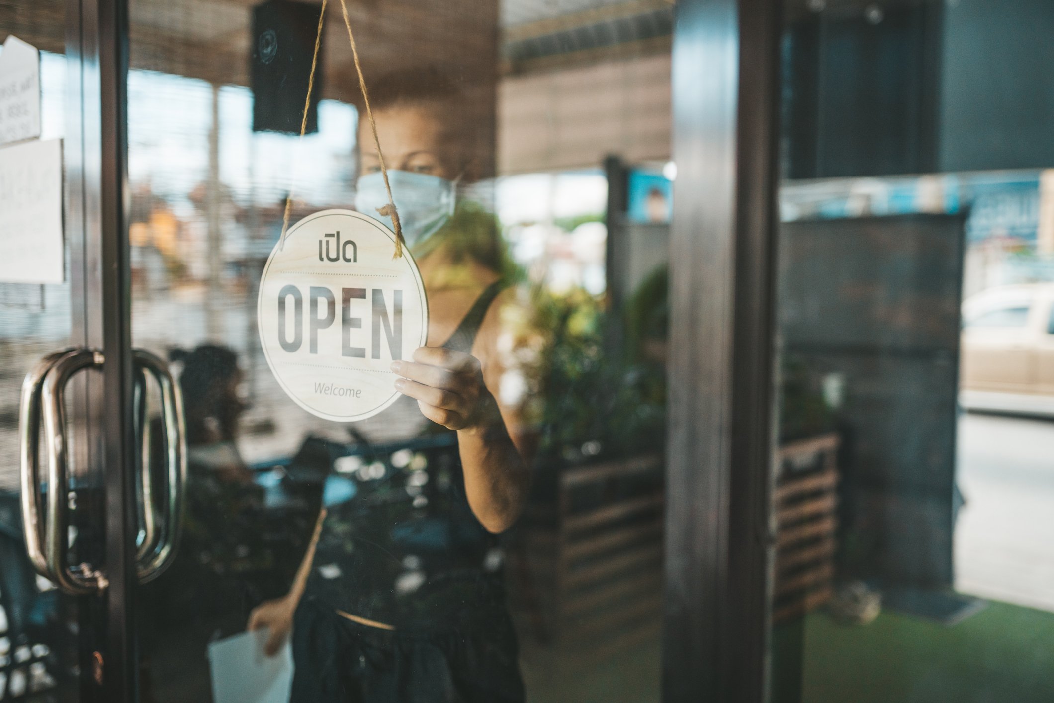 Young woman placing open sign in restaurant window. 