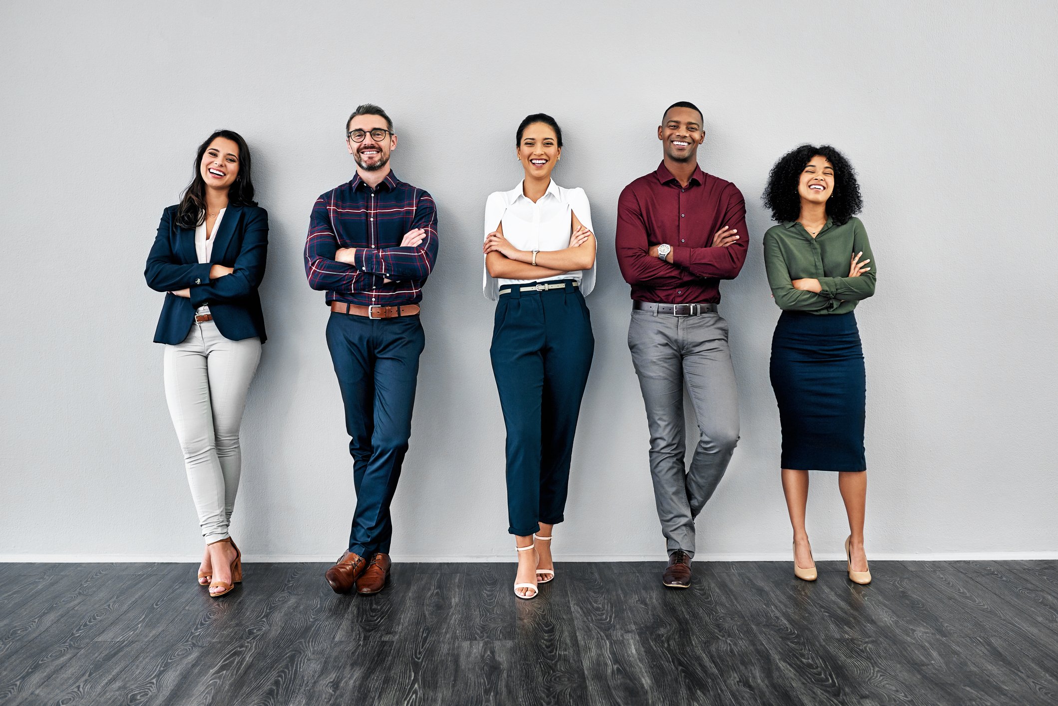 Five young professionals standing confidently against a wall