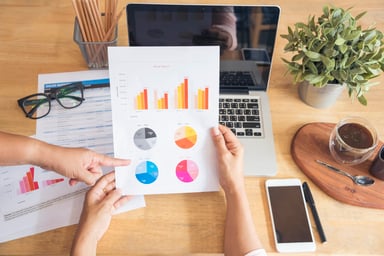 At a wooden table, people review financial charts 