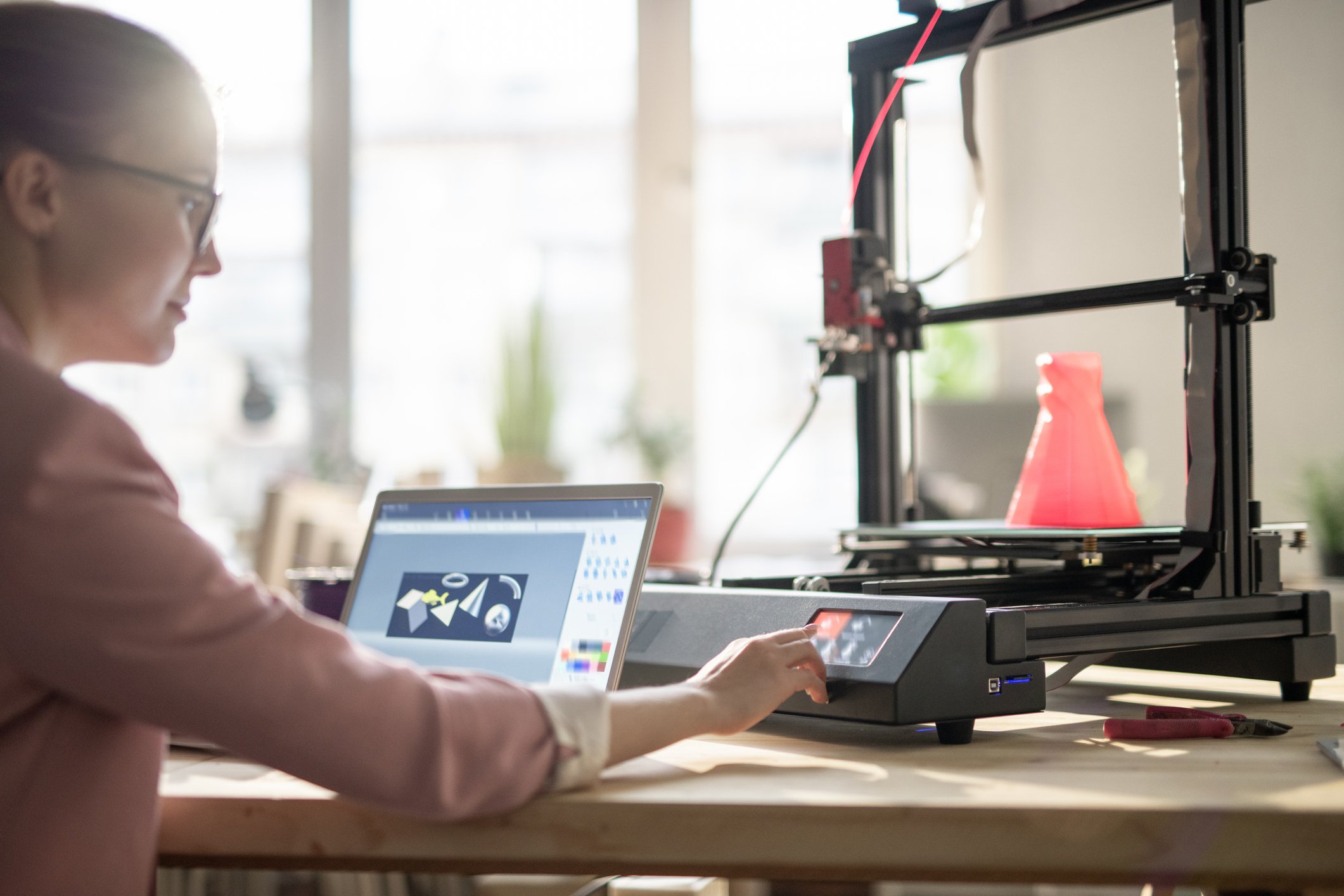 A woman uses a 3D printer.