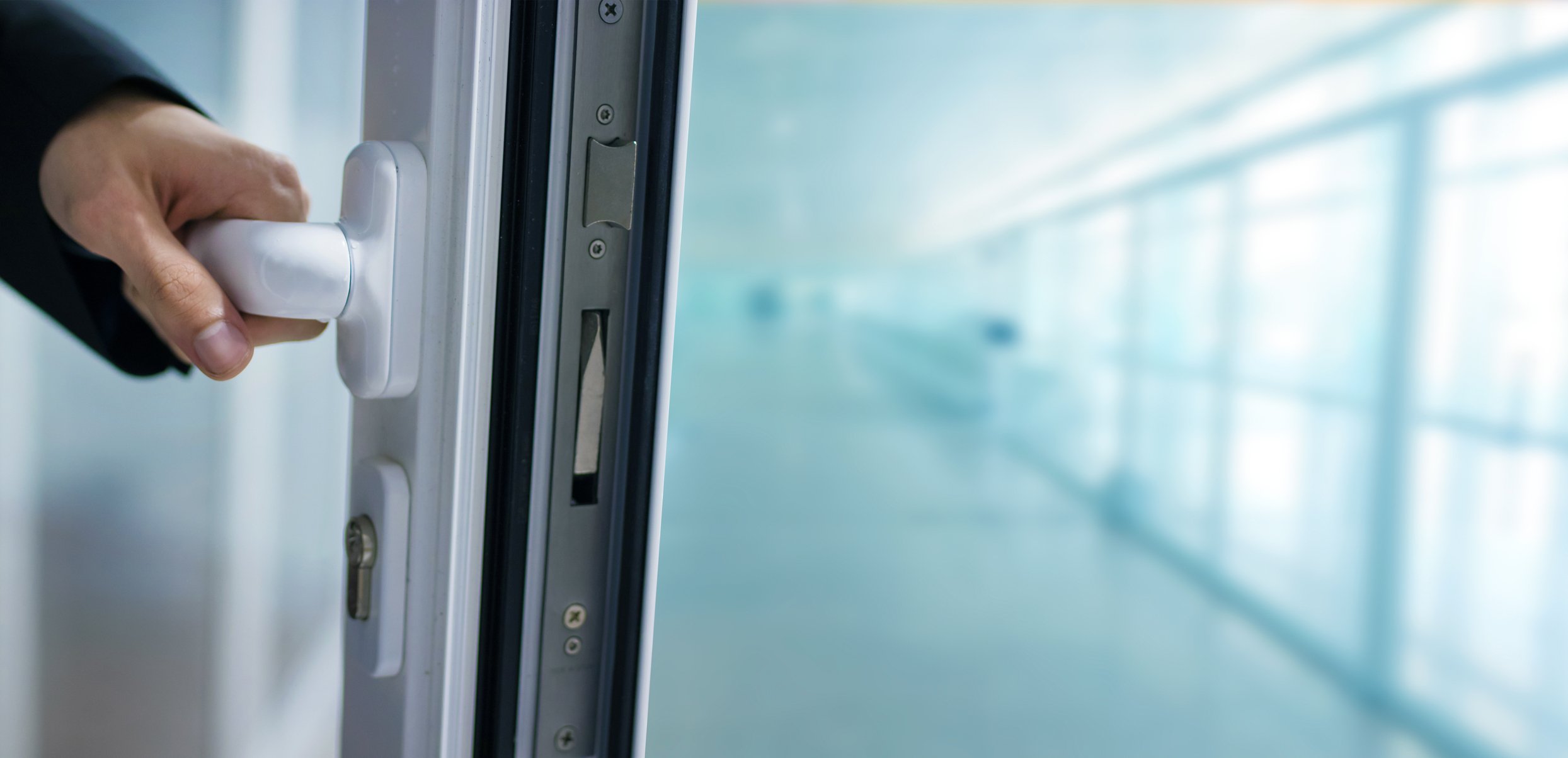 A hand opening a door in an office building.