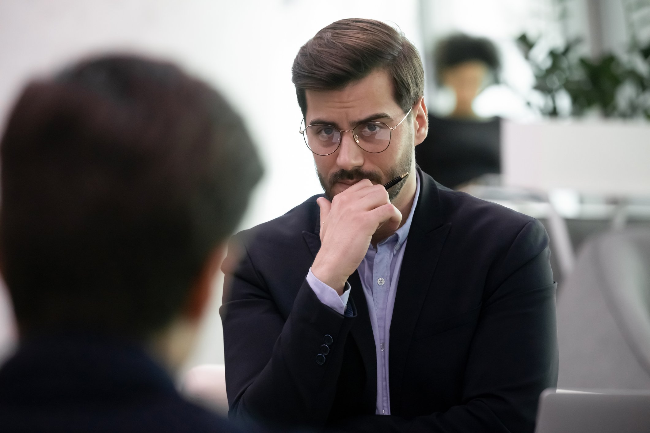 A skeptical person in glasses stares back at a person in the foreground. 