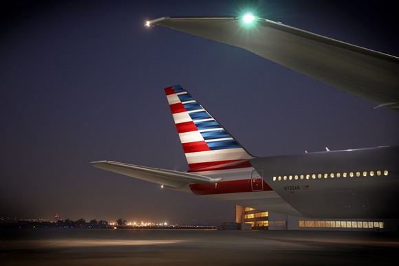 An American Airlines airplane tail lit up at night.
