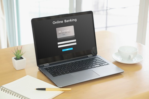 A laptop on a desk that is open to a page that says online banking and includes log in.