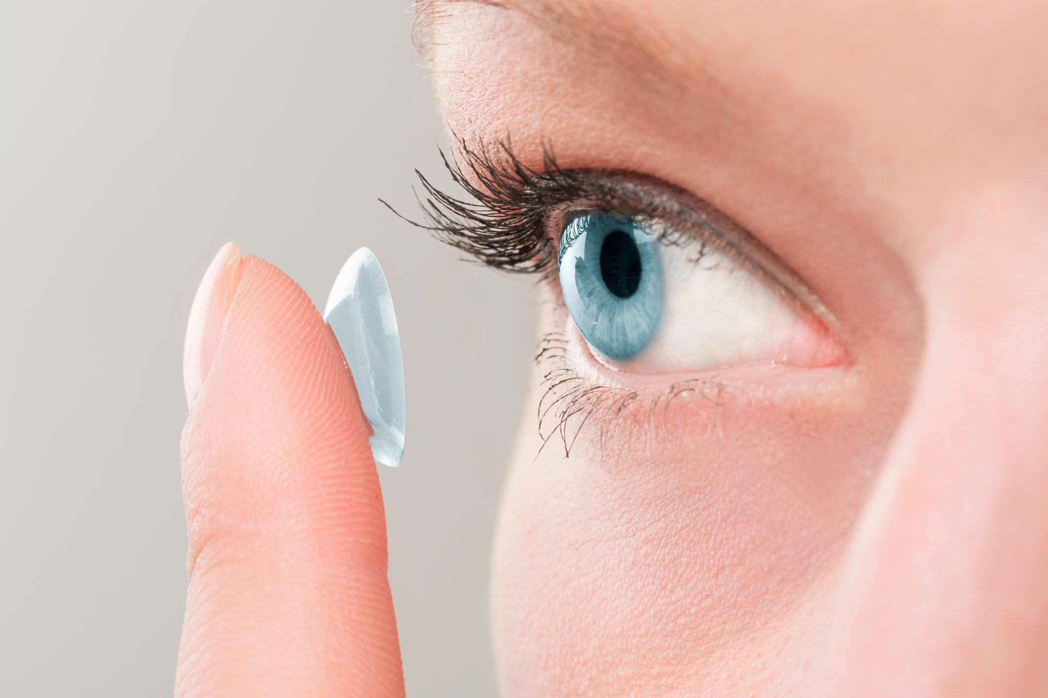 close-up of woman about to put contact lens in bright blue eye