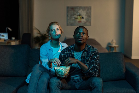 A couple watching TV and eating popcorn