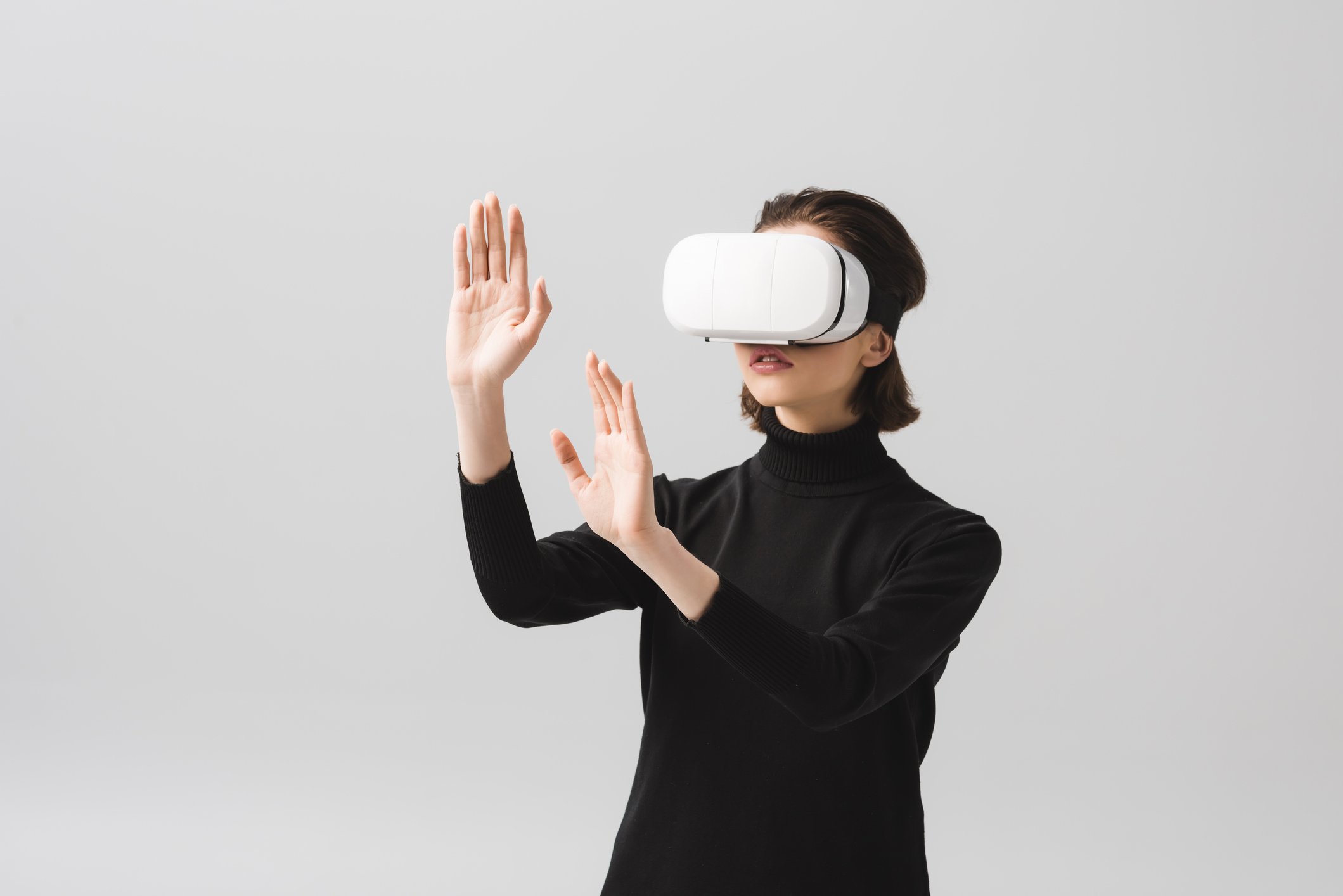 Young woman raising hands while wearing a virtual reality headset.