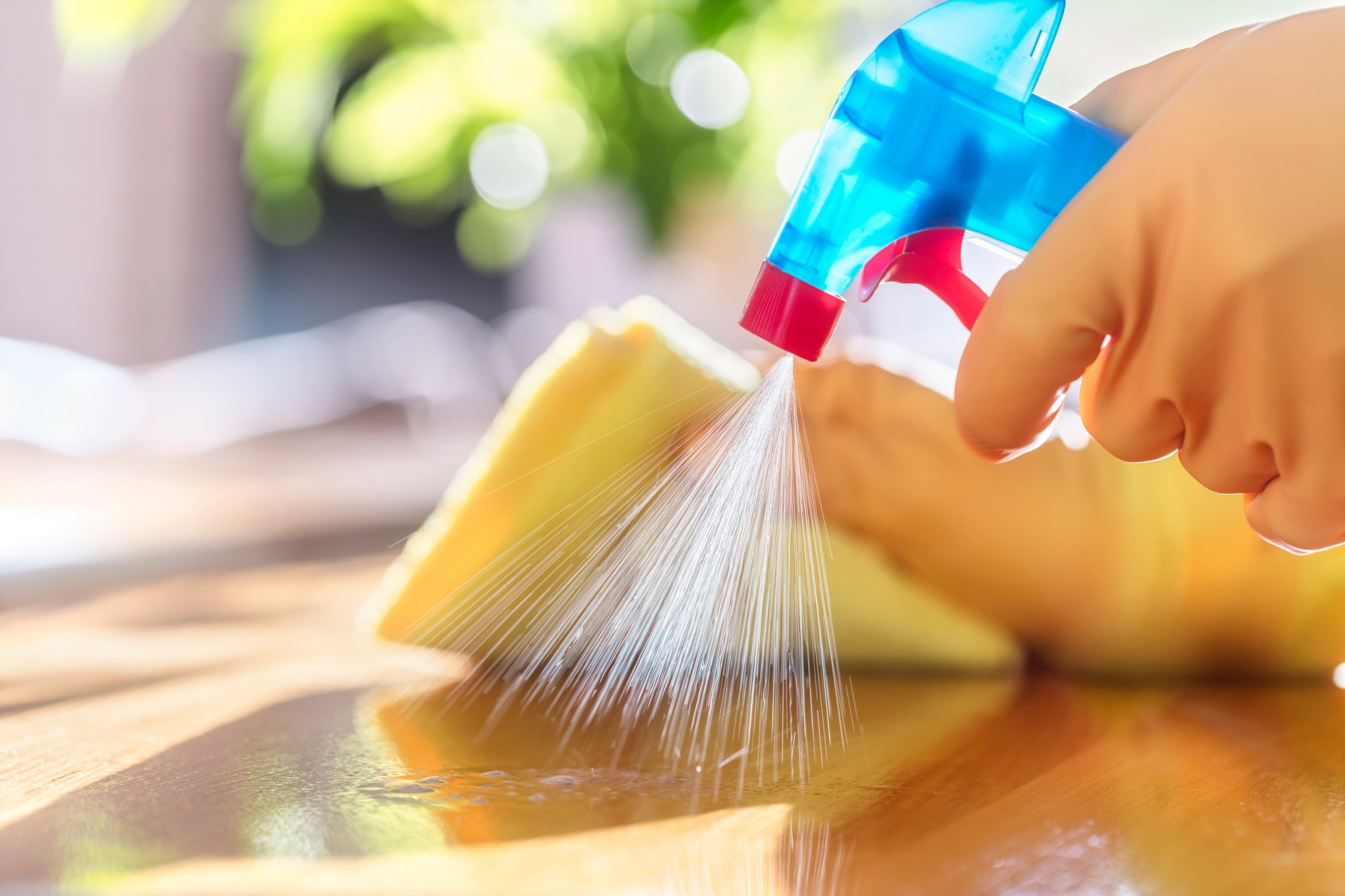 A person cleaning a surface with a spray bottle and cloth. 