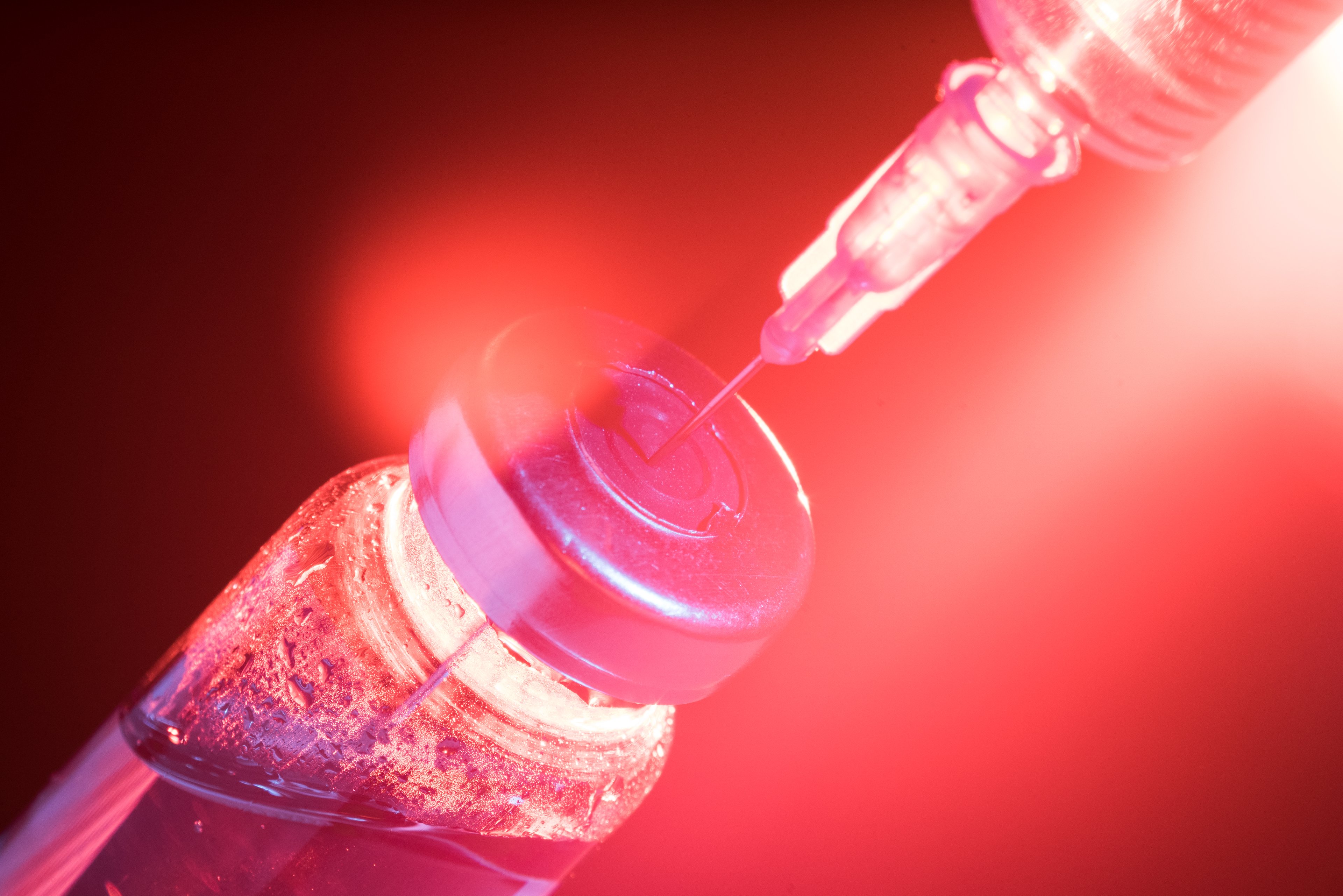 Red image of a vaccine vial and syringe. 