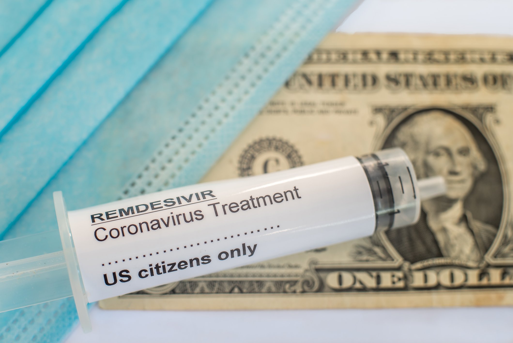 A coronavirus mask, a dollar bill, and a labeled syringe of Remdesivir that says U.S. citizens only