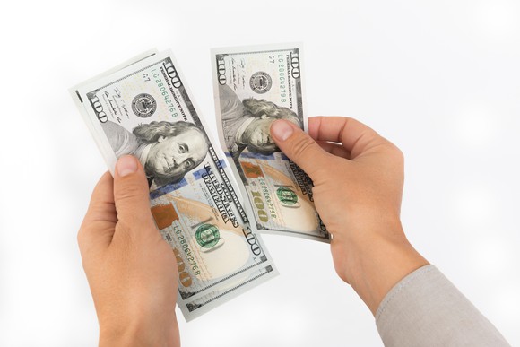 Hands holding $100 bills. 