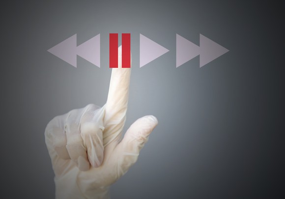 Gloved hand pressing pause button. 