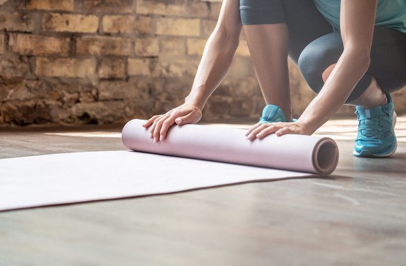Woman rolling out a yoga mat.