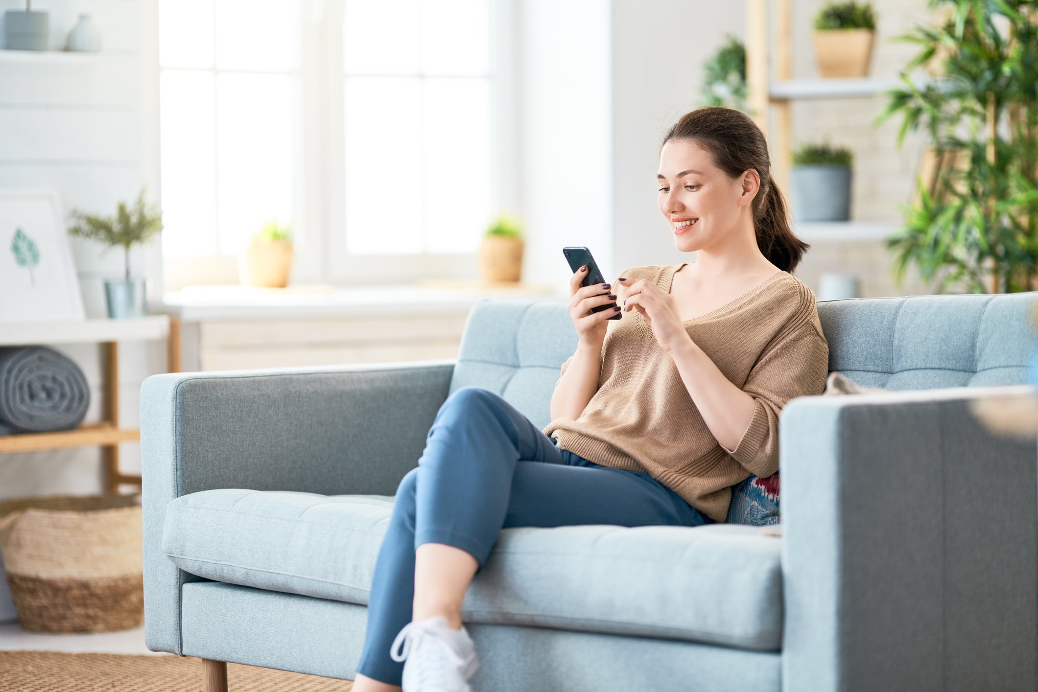 A woman sitting on a couch and using a mobile phone.