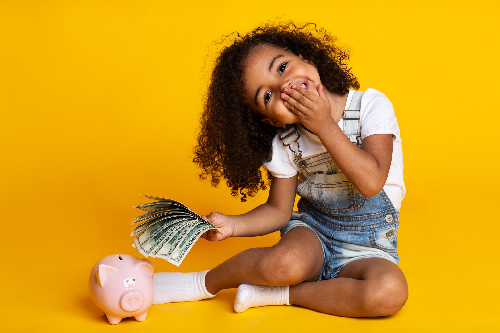 Little girl with a sheaf of money and a piggy bank.