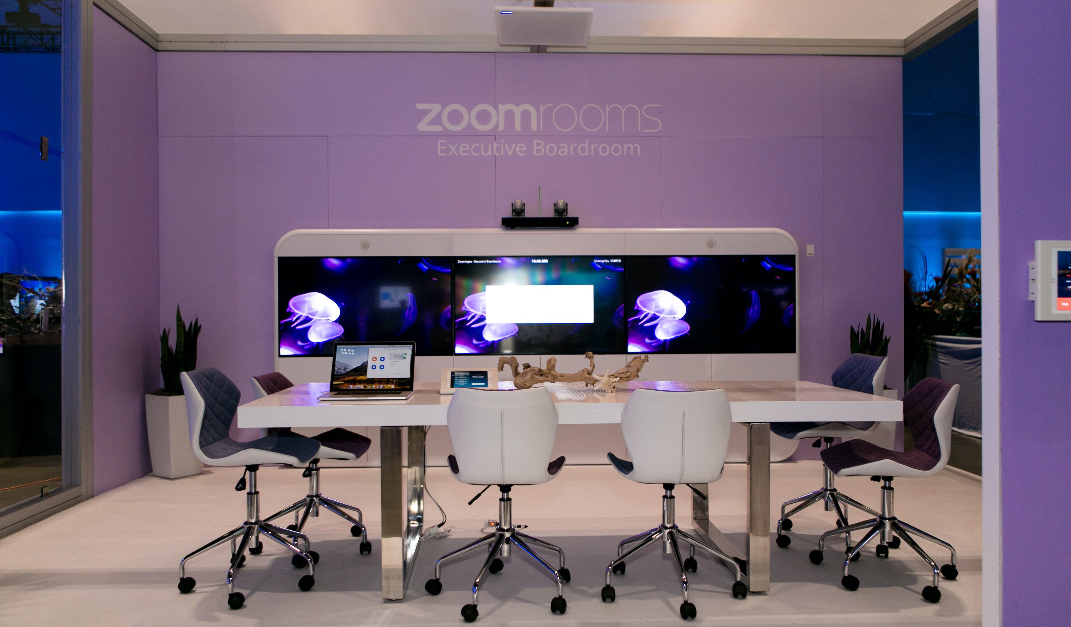 A Zoom Room with a white conference table and chairs