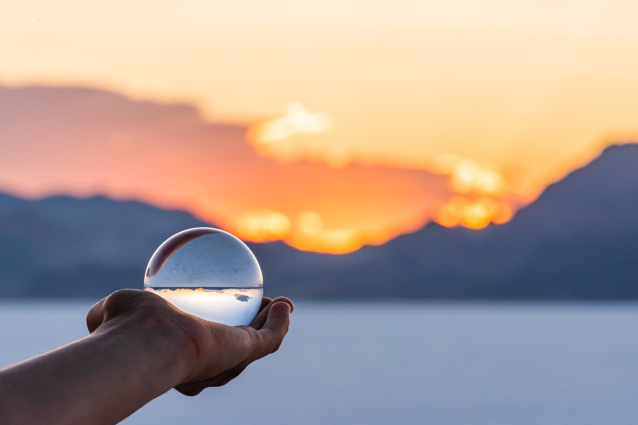 Someone holding out a crystal ball, looking out over a blurred horizon. 