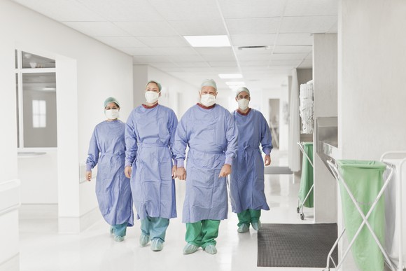 Doctors in masks walking down a hospital hallway.