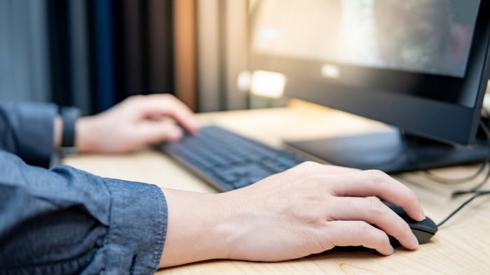 A person sitting at a desk using a computer. 