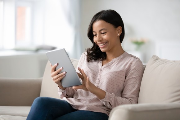 Lady smiling while tapping on tablet computer