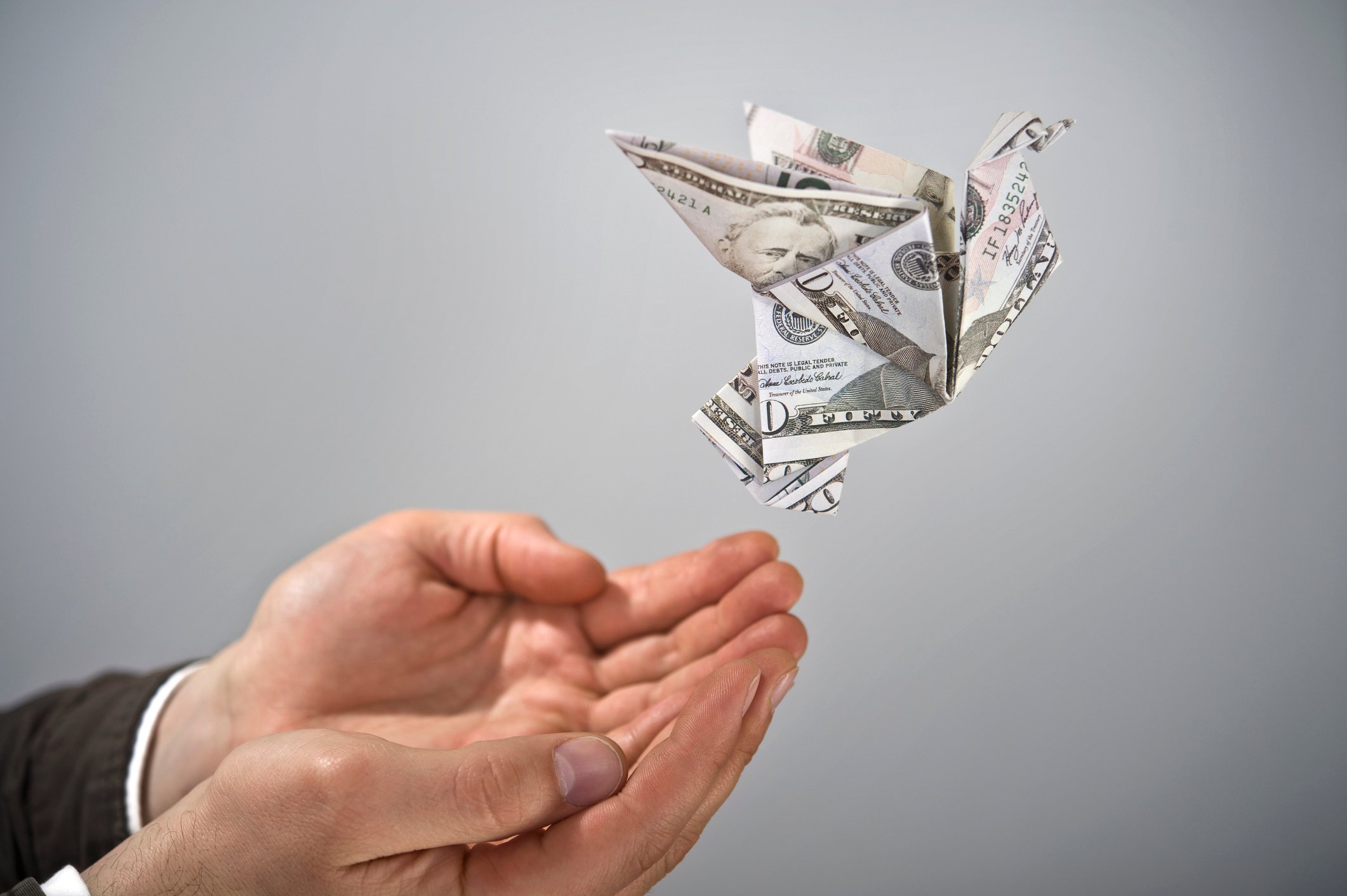 Dollar origami flying from a persons hand