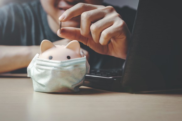 Young man playing with a coin above a masked piggy bank.