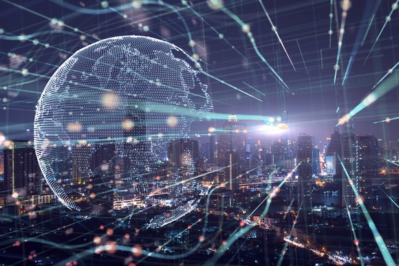 A digital globe overlaid across a downtown city landscape at night. 