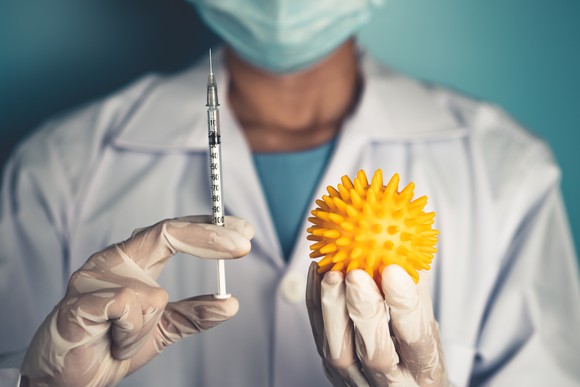 Doctor holding syringe and model coronavirus