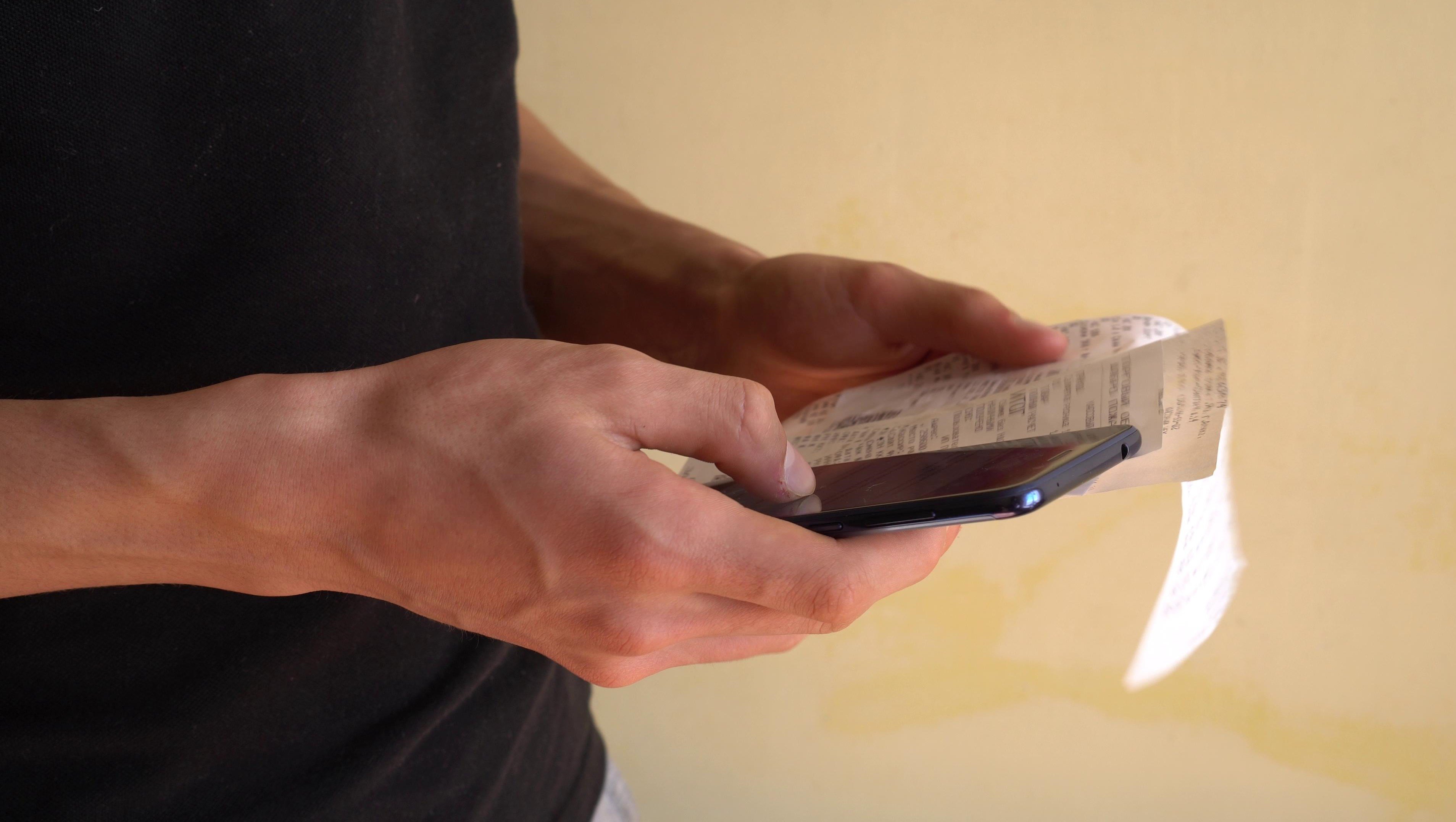 Man holding receipts and smartphone