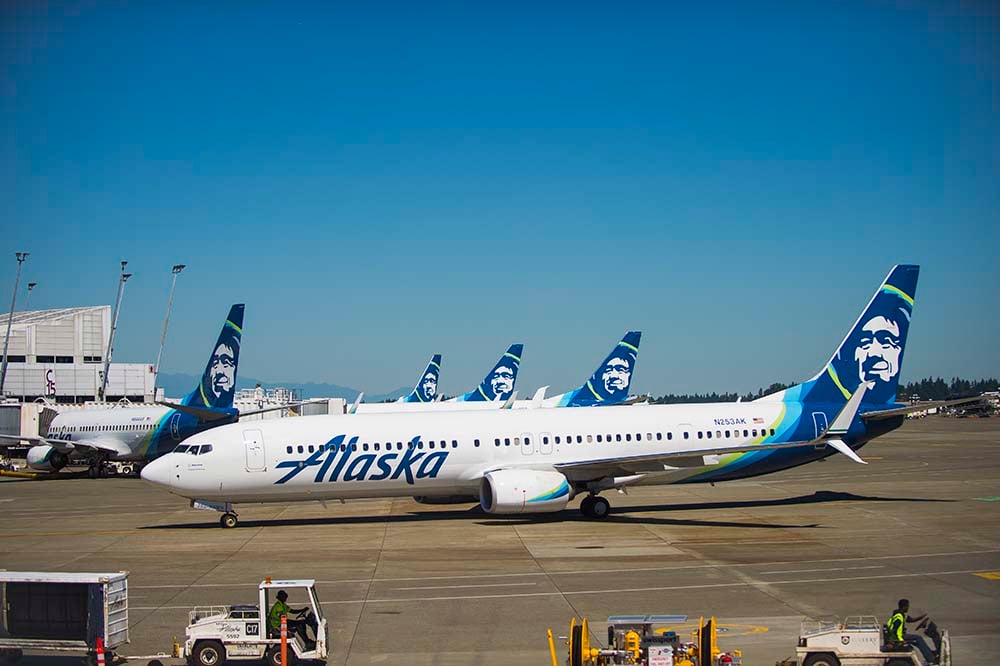 A number of Alaska planes parked in a row at the terminal.