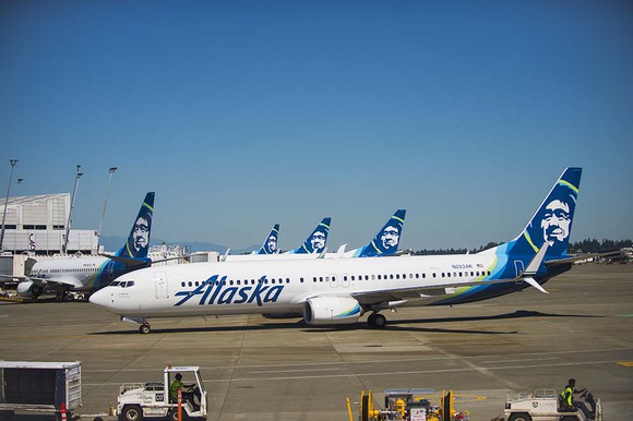 A number of Alaska planes parked in a row at the terminal.
