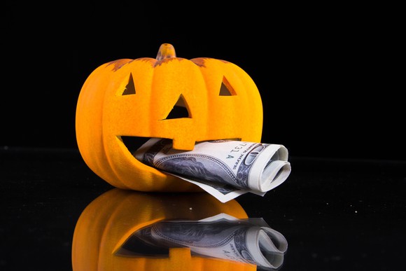A jack-o'-lantern with a hundred-dollar bill in its mouth.