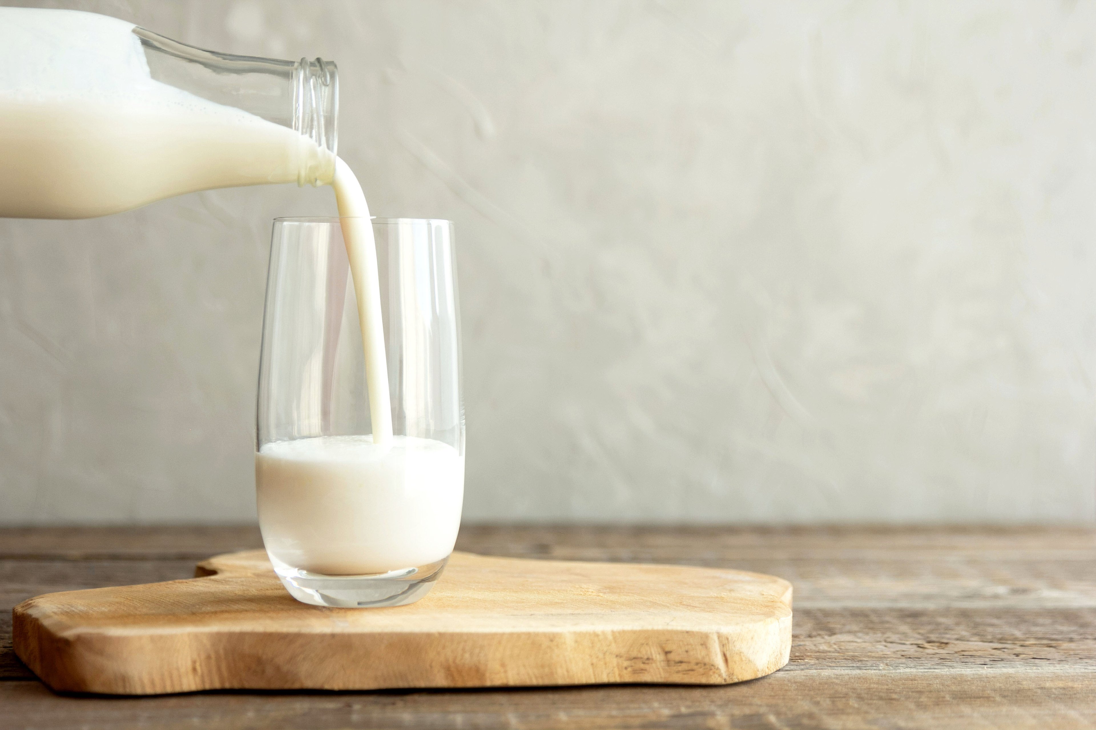 Milk being poured out of a glass bottle into a drinking glass.