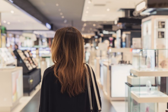 A woman walks through the cosmetics department in a department store,