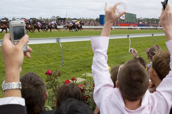 Spectators cheering at a horse race. 