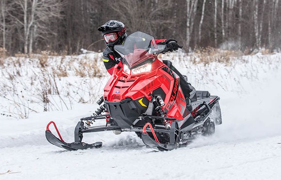 A snowmobile rider leans out to the right