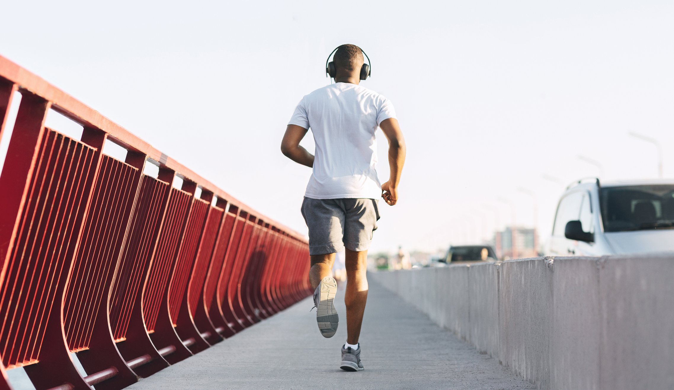 Man jogging along bridge with headphones