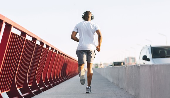 Man jogging along bridge with headphones