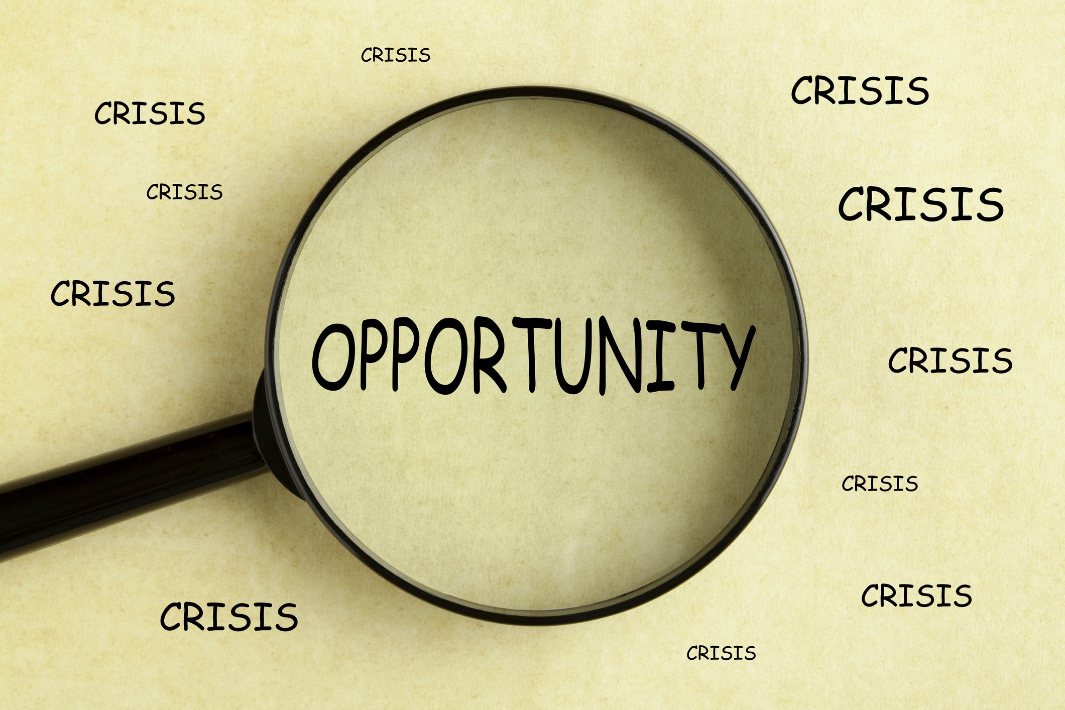 A magnifying glass over the word opportunity surrounded by duplicates of the word crisis.