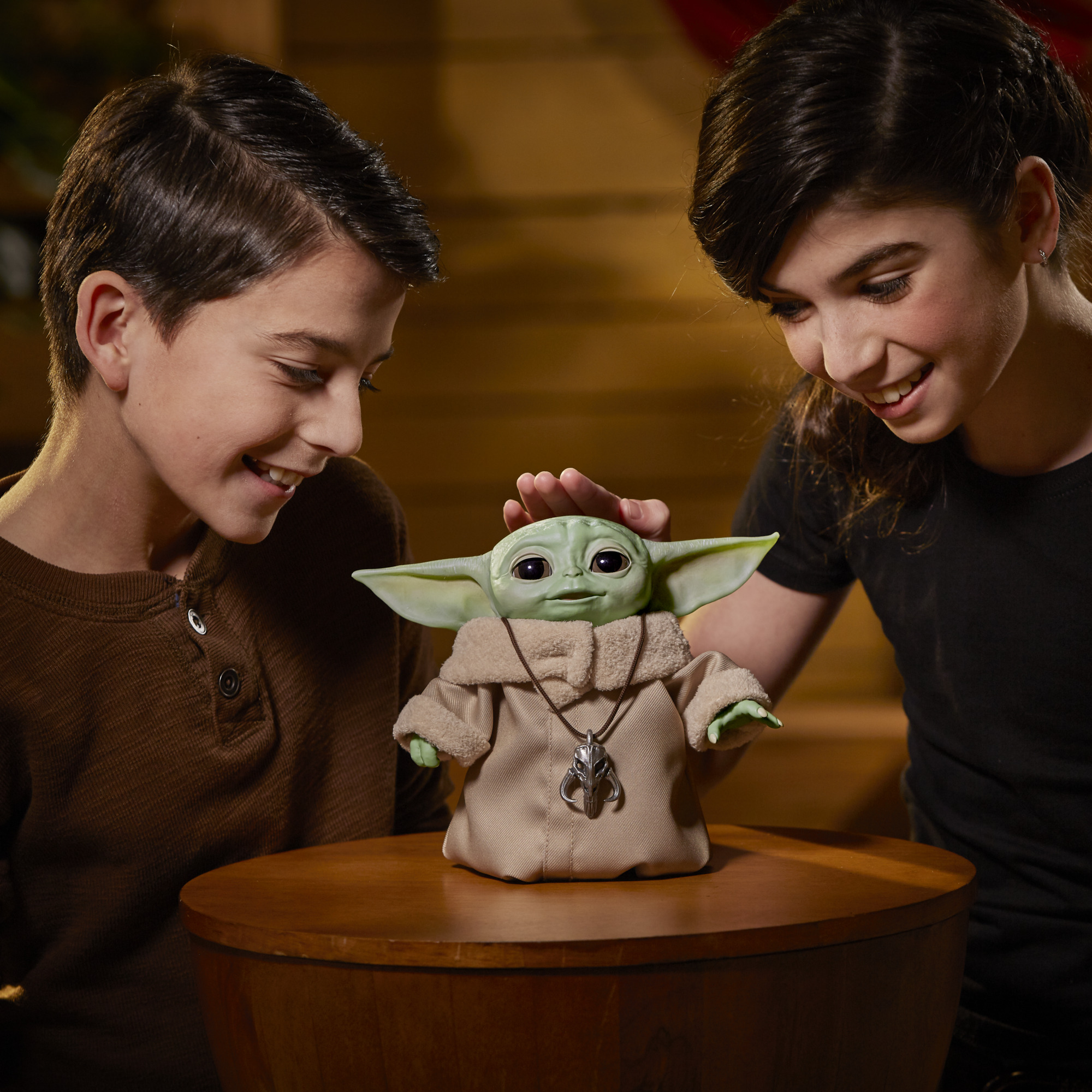 A young boy and girl playing with a Baby Yoda toy.